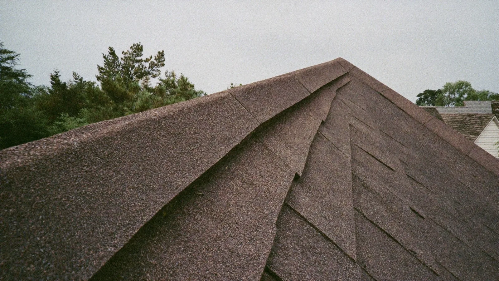 A close view along the hip of an asphalt shingle roof, showing the stepped shingle courses meeting at the hip ridge