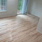 Spacious living room with newly installed light hardwood flooring and fresh paint.