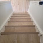 Newly installed hardwood staircase viewed from the bottom with clean white trim.