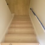 ight oak wooden staircase renovation with white side walls and modern finish.